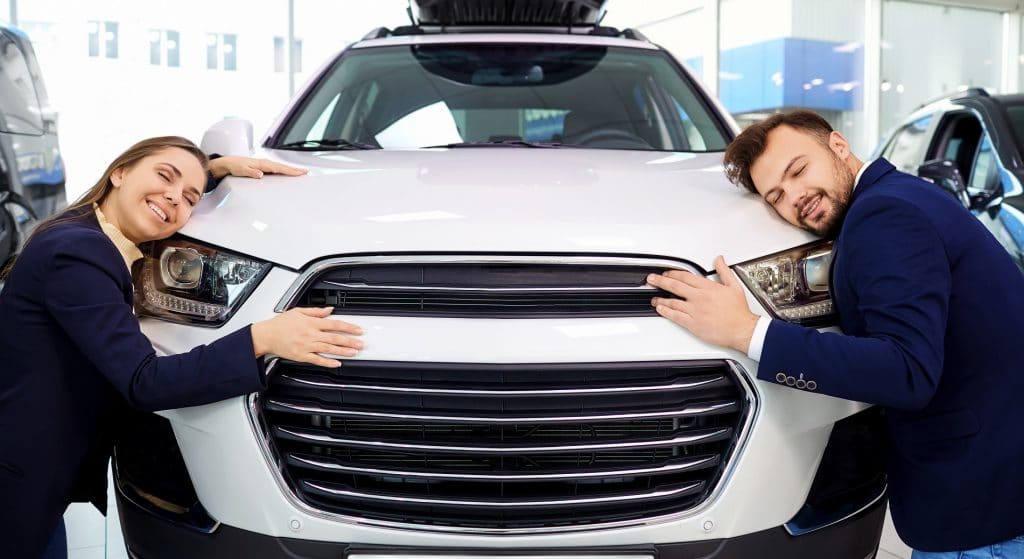 Couple Smiling Embracing Car Auto In Auto Salon